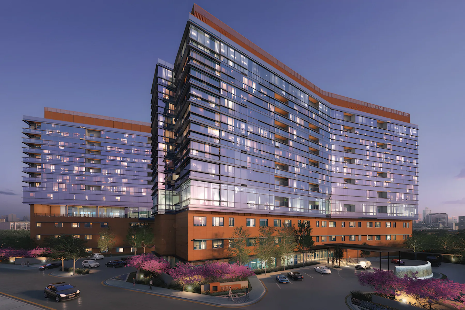 A senior living tower lit up at dusk above a landscaped drive