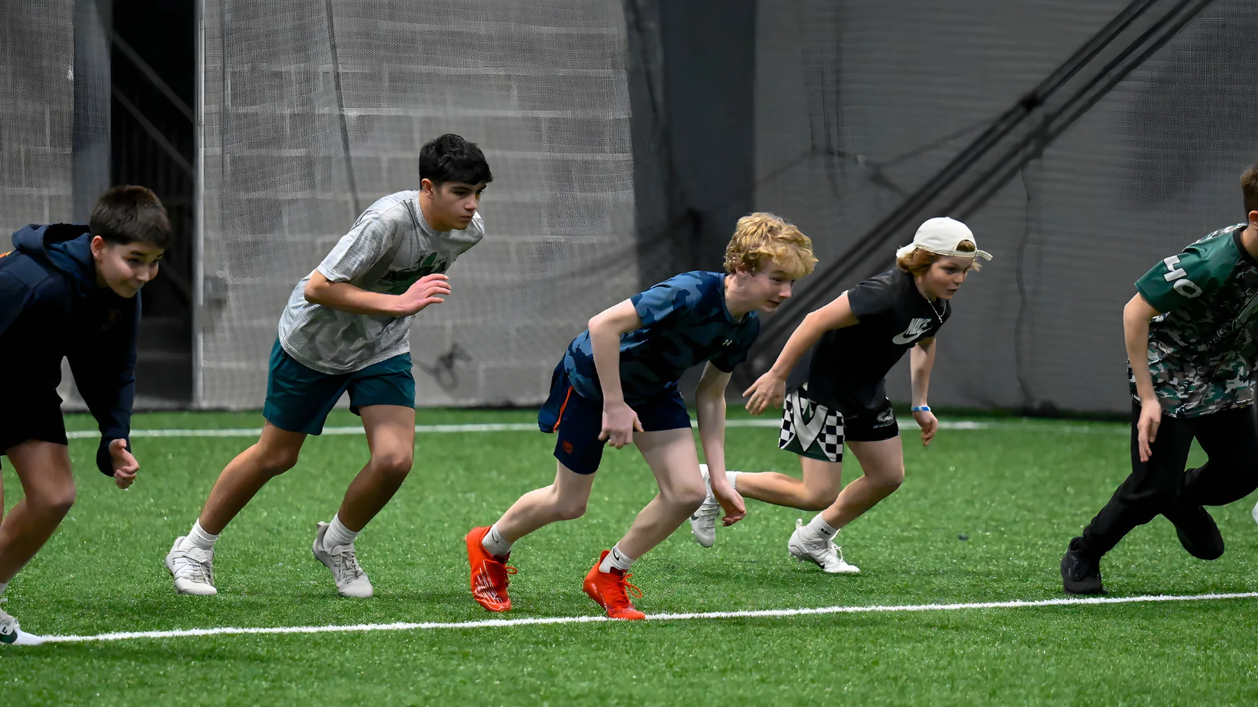Young athletes sprinting off the line on indoor turf