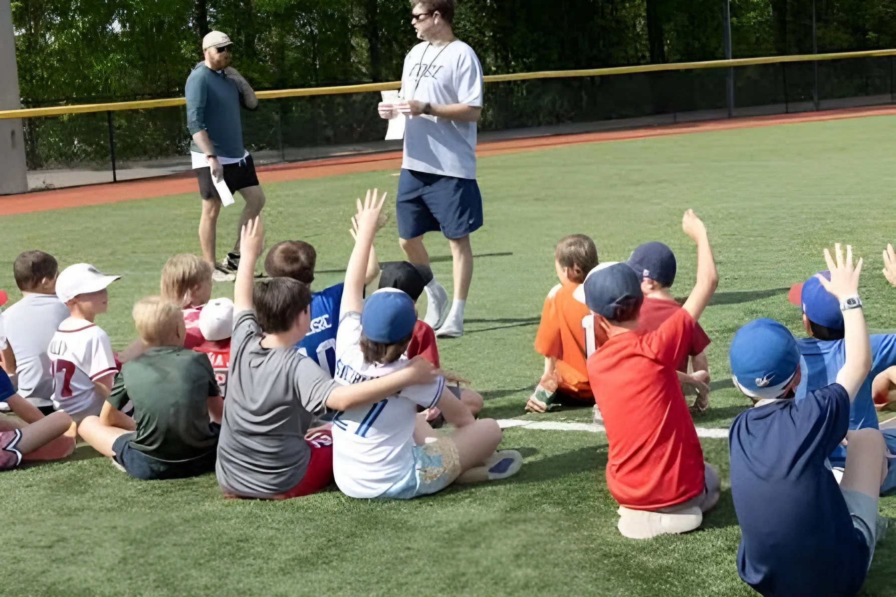 A coach talking to young athletes sitting on the field