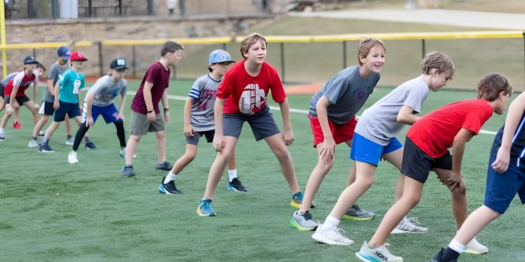 A row of young athletes in a ready stance on an outdoor field