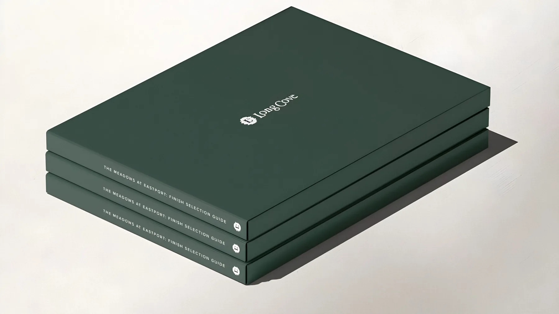 A stack of green Long Cove books on a pale surface