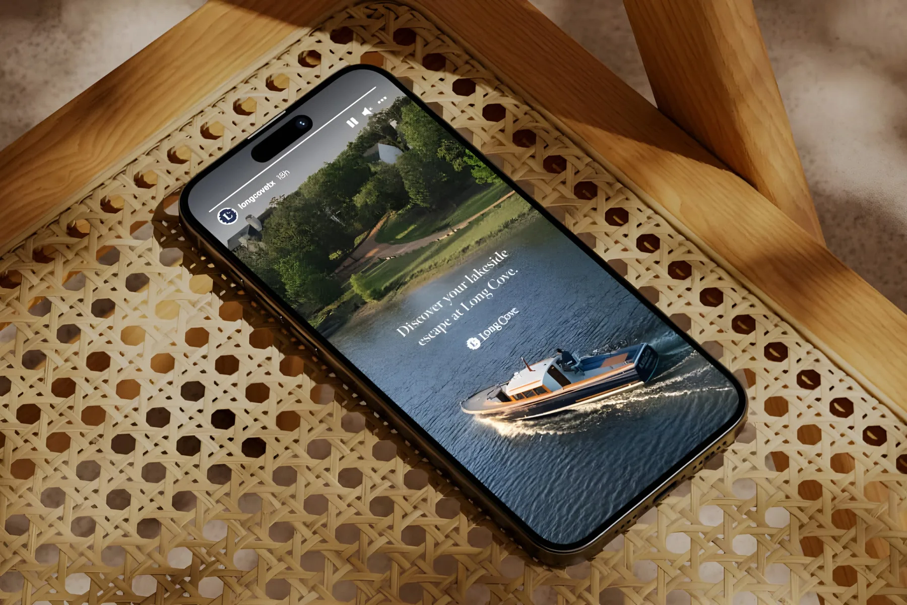 A phone showing a Long Cove post, resting on a cane chair