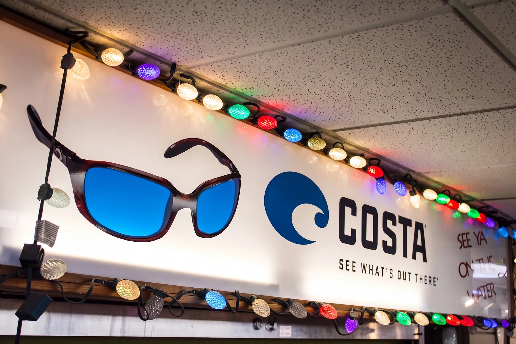 A lit Costa sunglasses banner inside Mark’s Outdoors