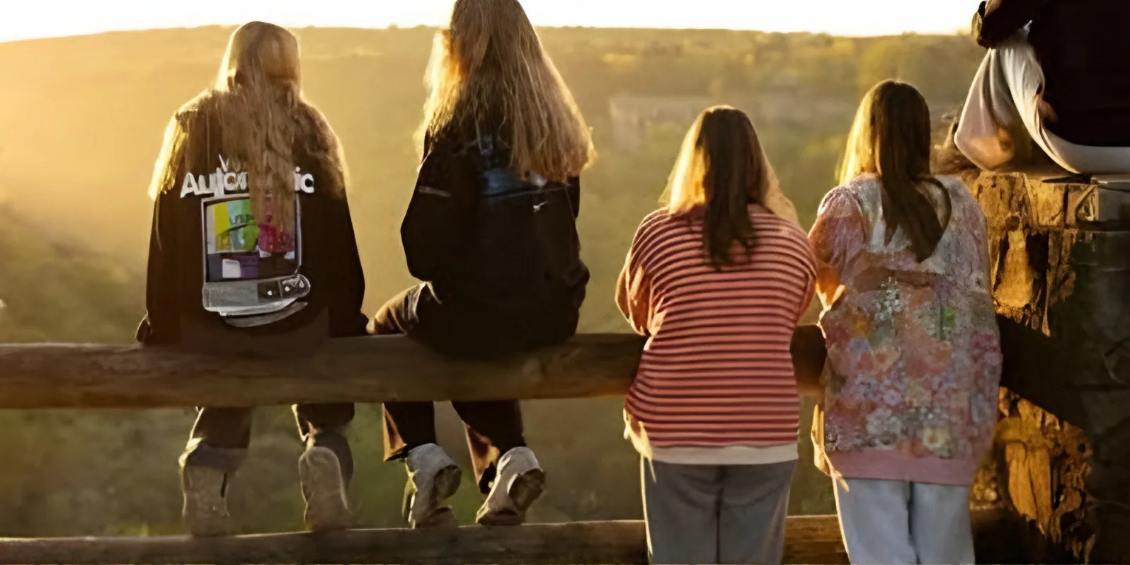 Club members watching the sunrise from a wooden fence