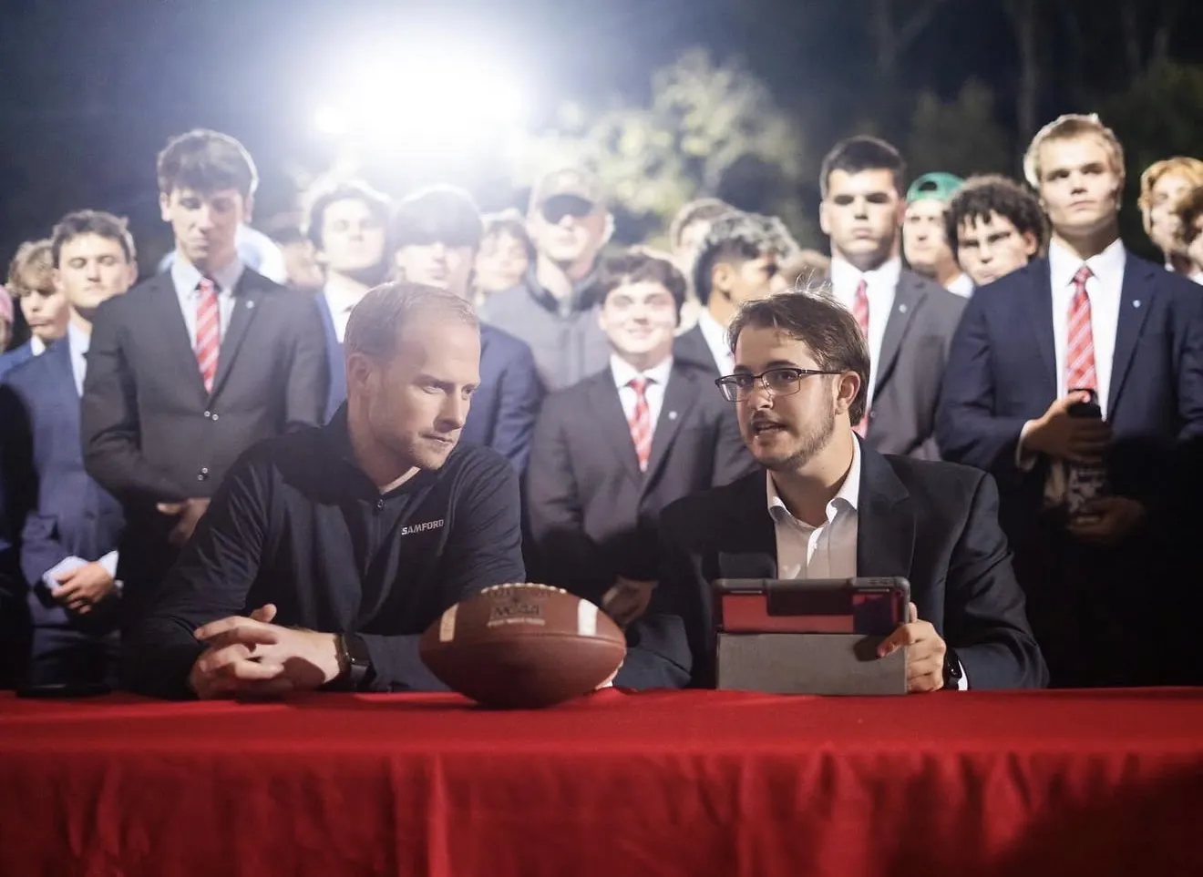 Hosts and students gathered at the GameDay picks desk under the lights